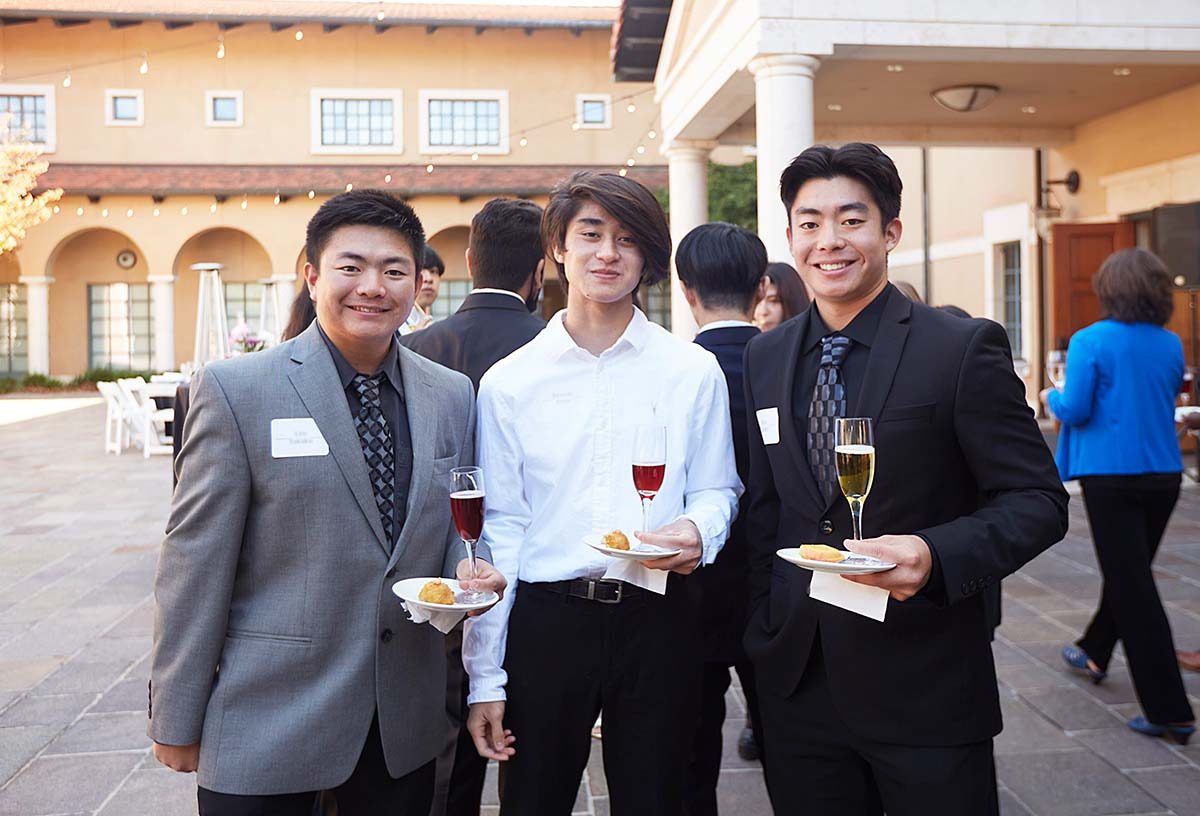 Soka students holding plate and wine glass during networking practice 