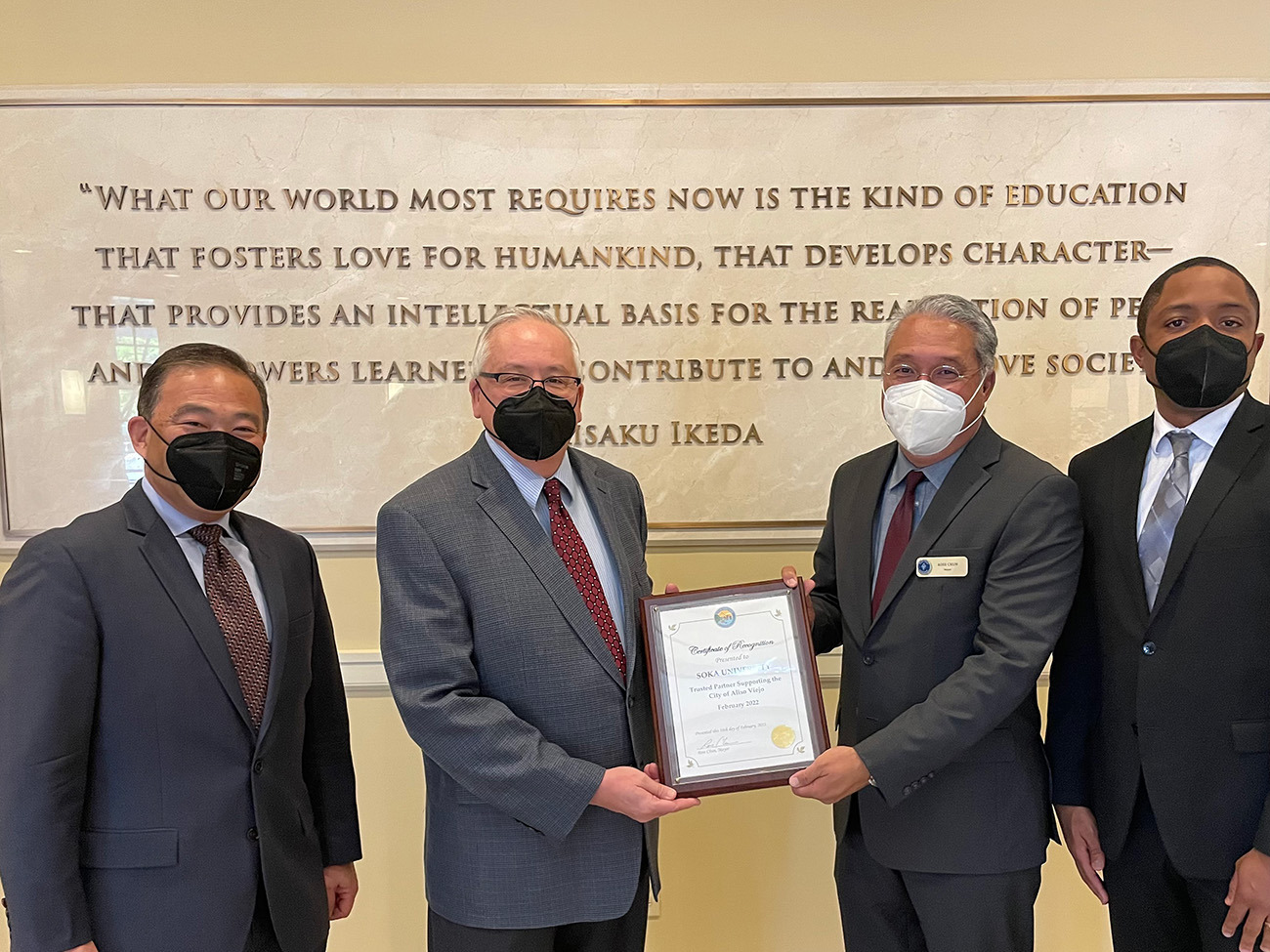 Men holding certificate of recognition in SUA Founders Hall 