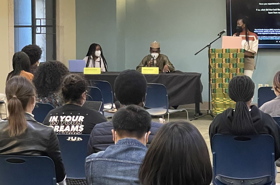 A crowd listens to panelists engaged in discussion during the Black history month event in the Student Affairs lobby