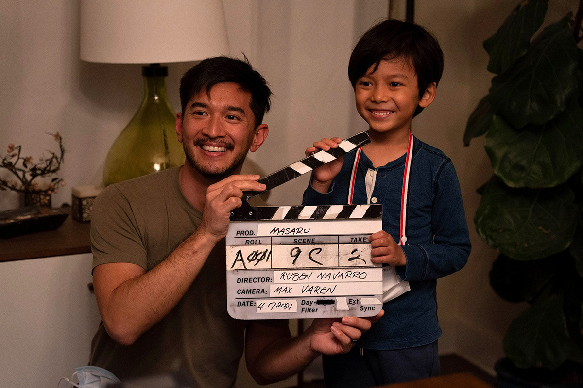 Michael Sasaki poses with a young male actor holding a clapperboard.