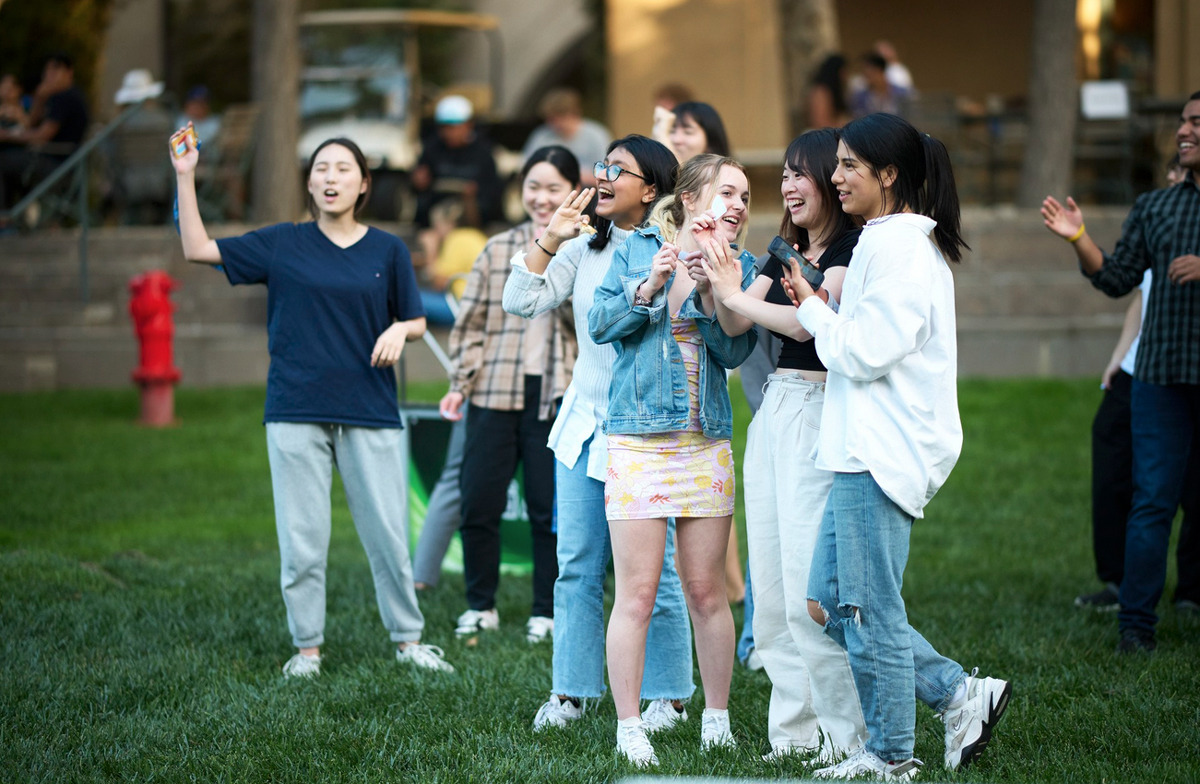 A group of students laugh together while enjoying the 21st Anniversary party