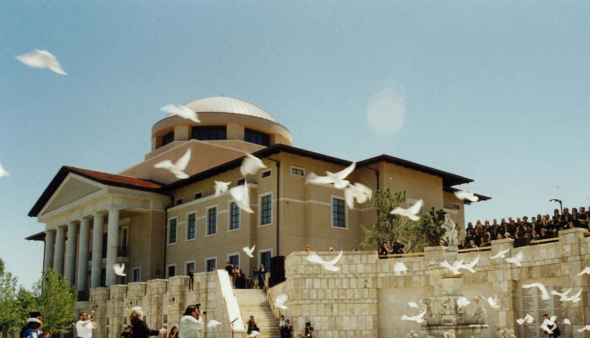 A flock of doves fly in front of Founders Hall