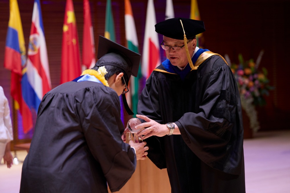 Kentaro Shintaku bows at President Feasel when he accepts the Founders Award