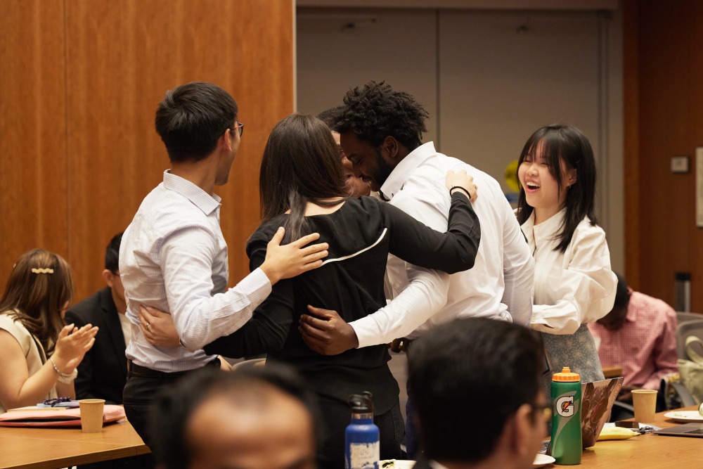 Students hug in celebration after being named the first-place winner of Impactathon.