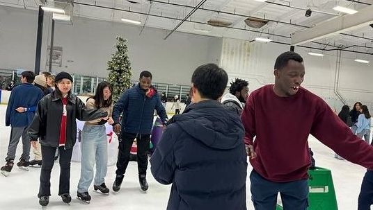 A large group of students smile as they ice skate together.