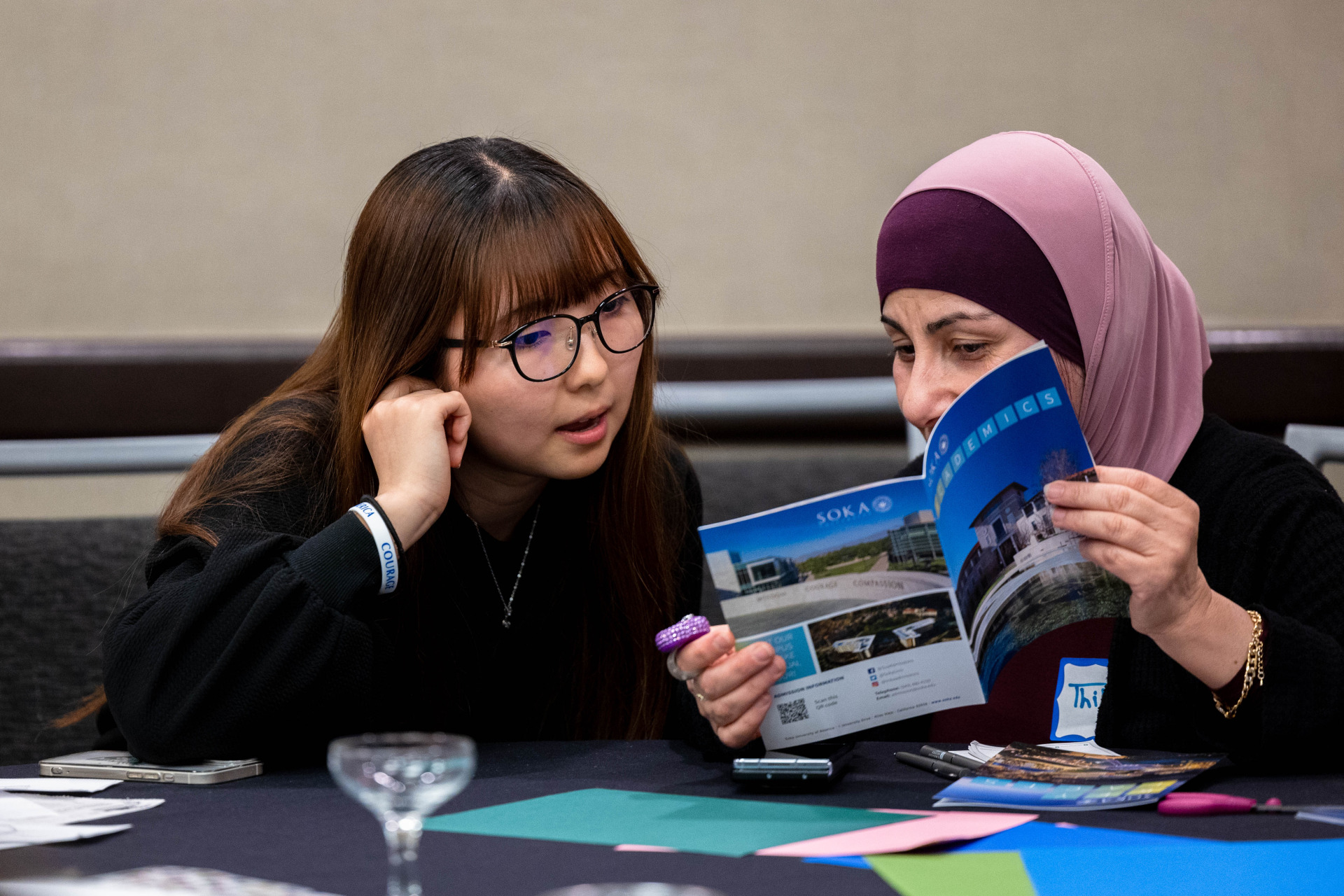 Two women look at a Soka brochure