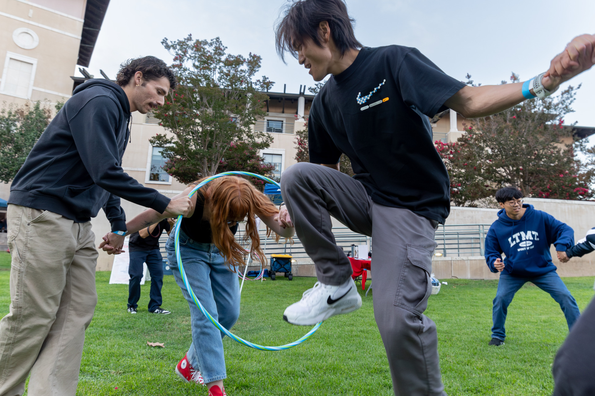 Students hold hands and try to move a hula hoop through a line of people as part of SUA's annual Welcome Back Community Event