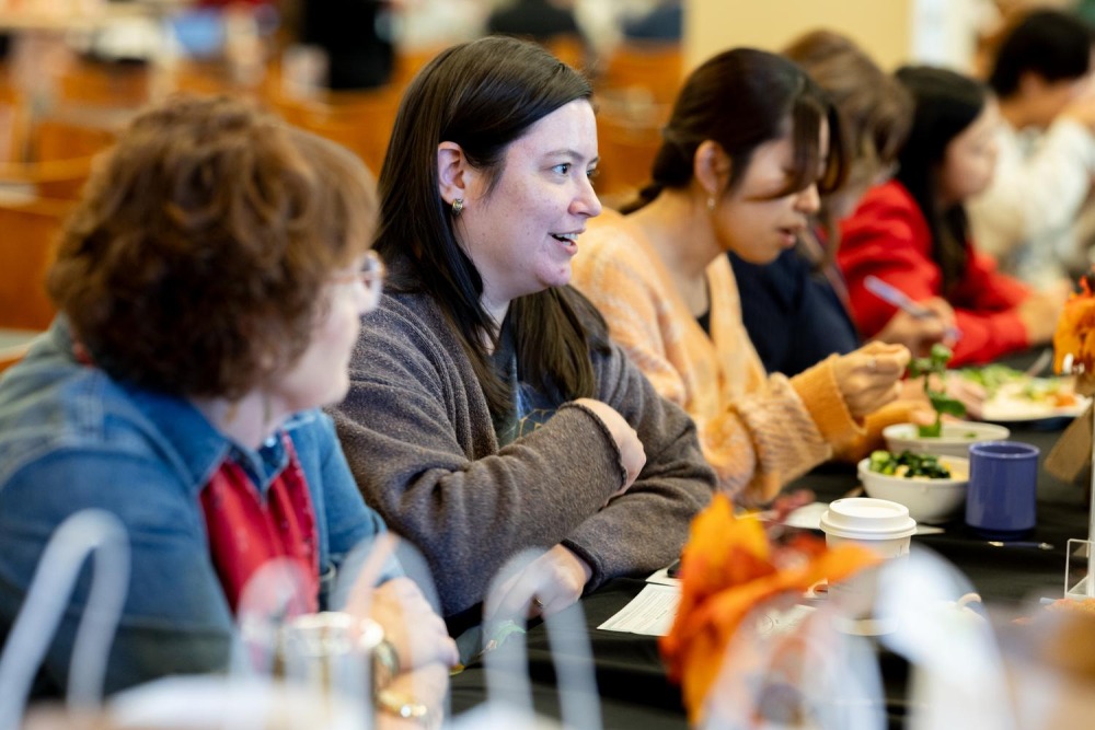 Participants at a "Dialogue Buddies" event engage in discussion while sharing a meal at a table decorated with autumn-themed accents.