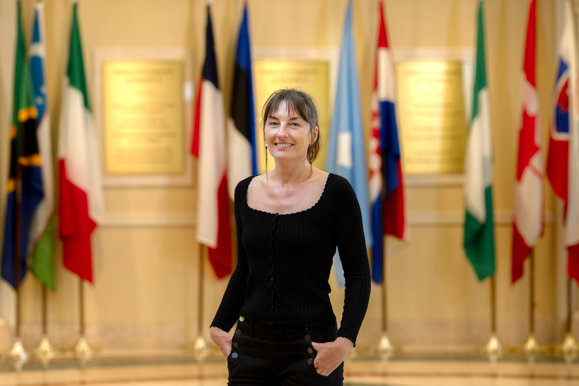 Sandrine Siméon, associate professor of French language and culture and director of the Language and Culture program stands in front of various countries' flags in Founders Hall.