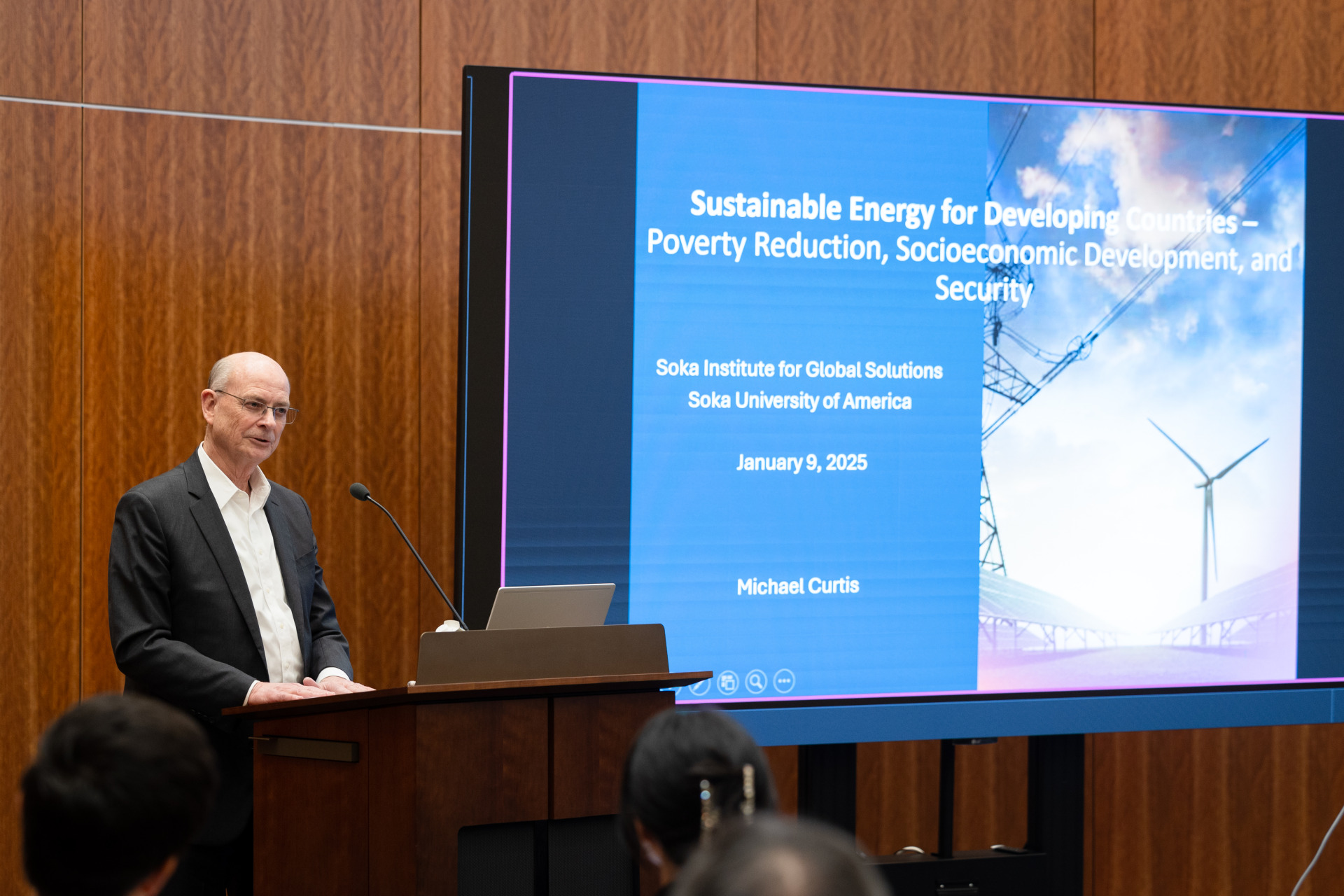 Dr. Michael Curtis stands at the podium beside his presentation during his Jan. 9 talk to the SUA community.