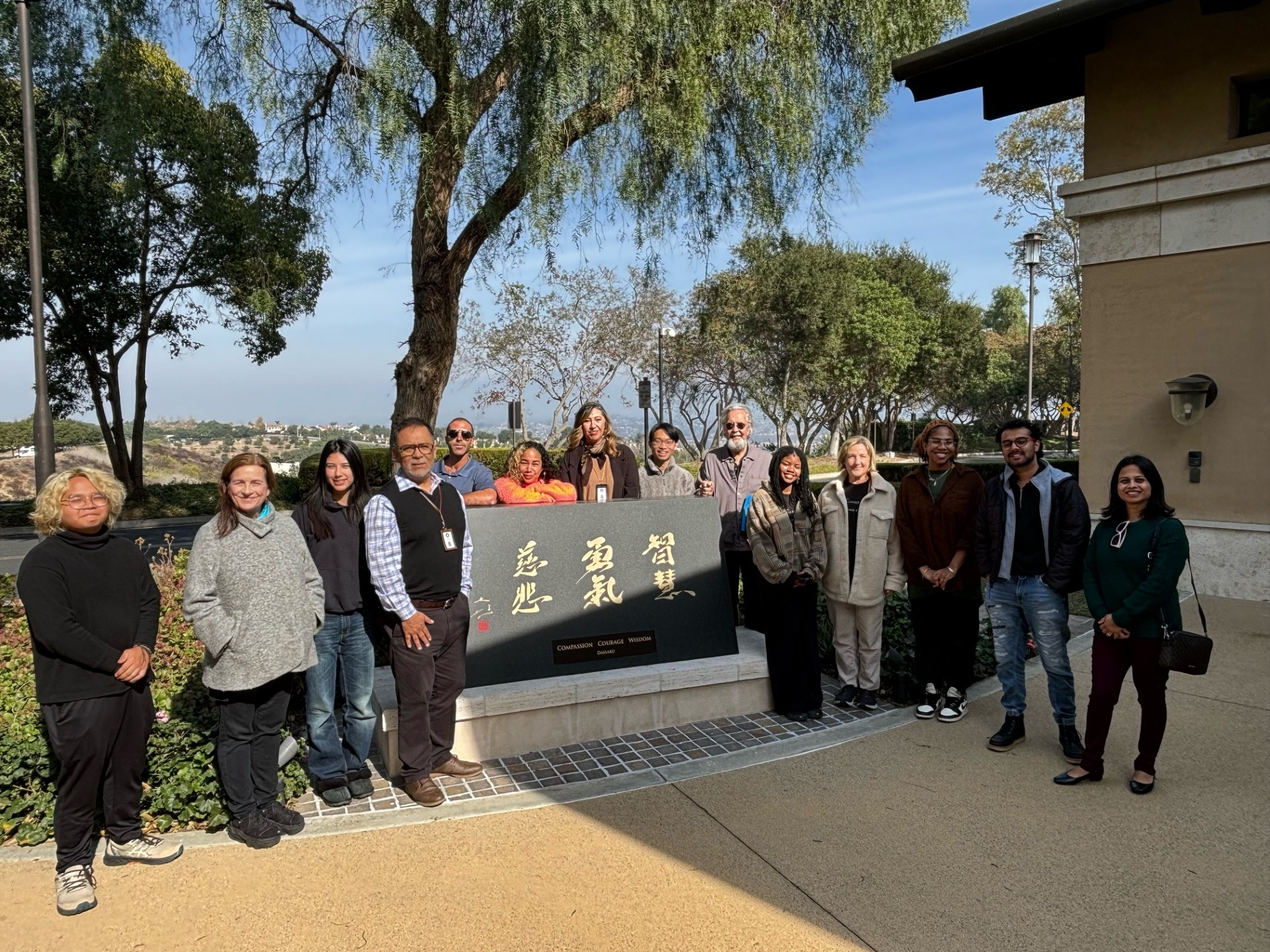 Writing Center staff gathered around a plaque titled "Wisdom, Courage, Compassion." 
