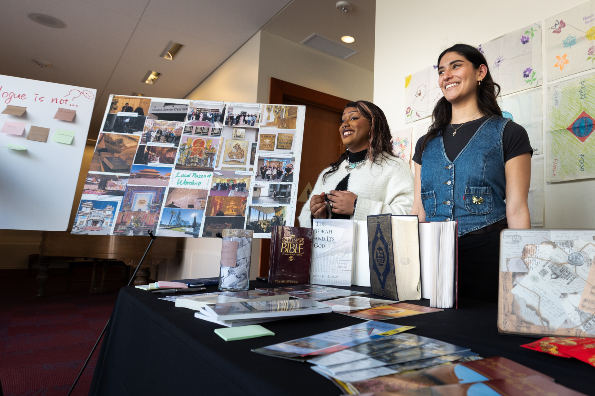 Two students smile as they stand with their research project during the winter block Learning Cluster Fair.