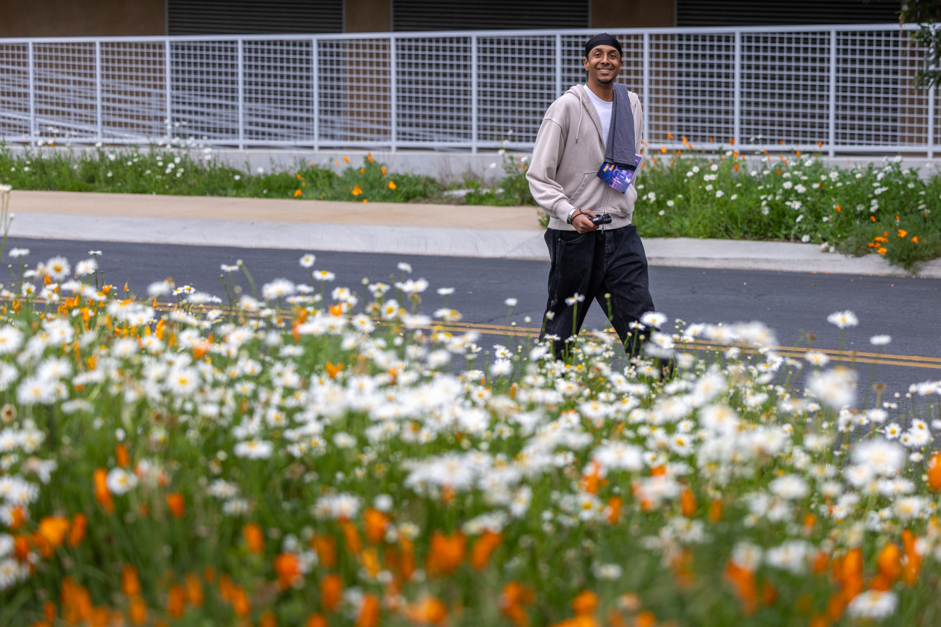 Lucas Colombo ’27 smiles at the camera as he walks among flowers on SUA's campus during the annual Heart of a Lion walk/run.