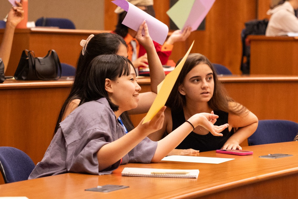Three students hold up pieces of colored paper during an exercise about the concept of dialogue.