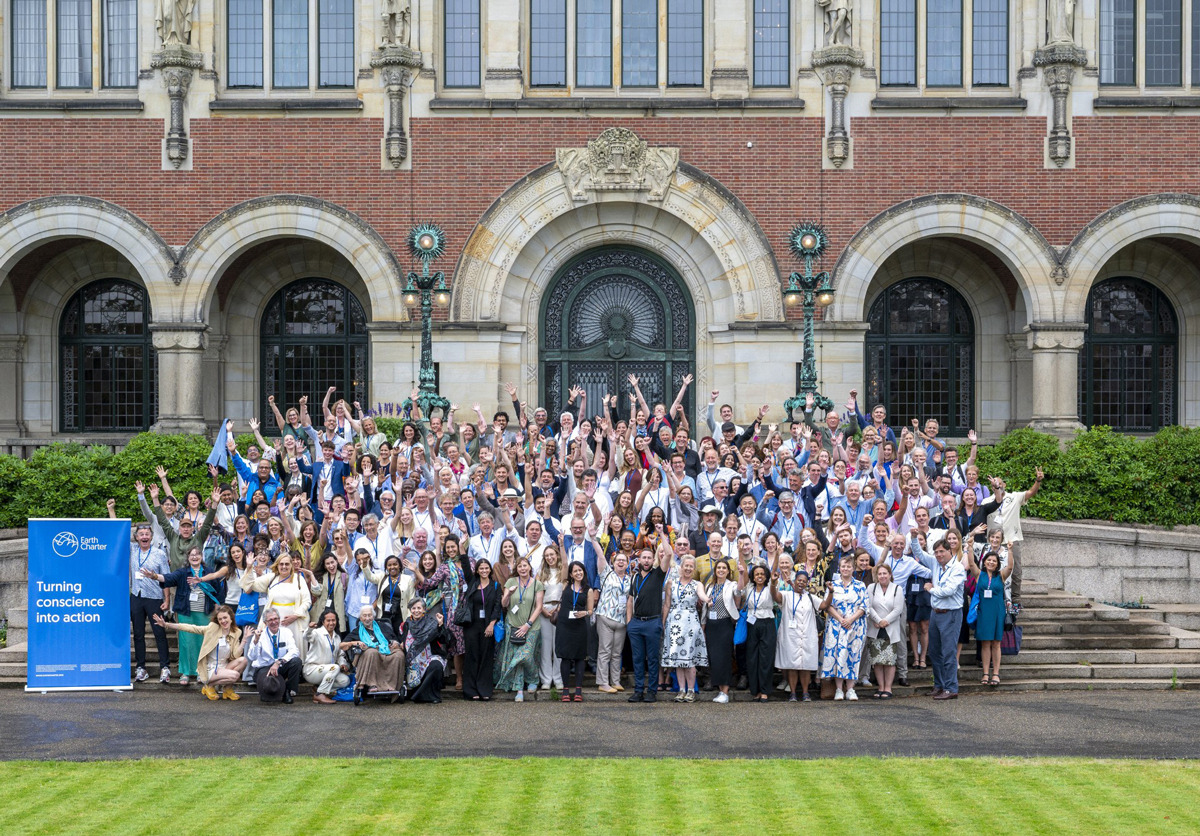 340 participants raise their arms and pose for a group photo during the 25th anniversary of Earth Charter event.