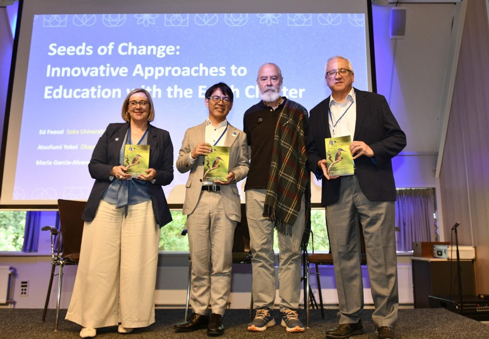 Four panelists pose holding an Earth Charter brochure