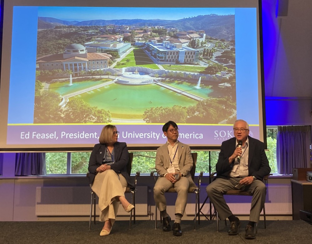 President Ed Feasel speaks into the microphone as he participates in a plenary panel session