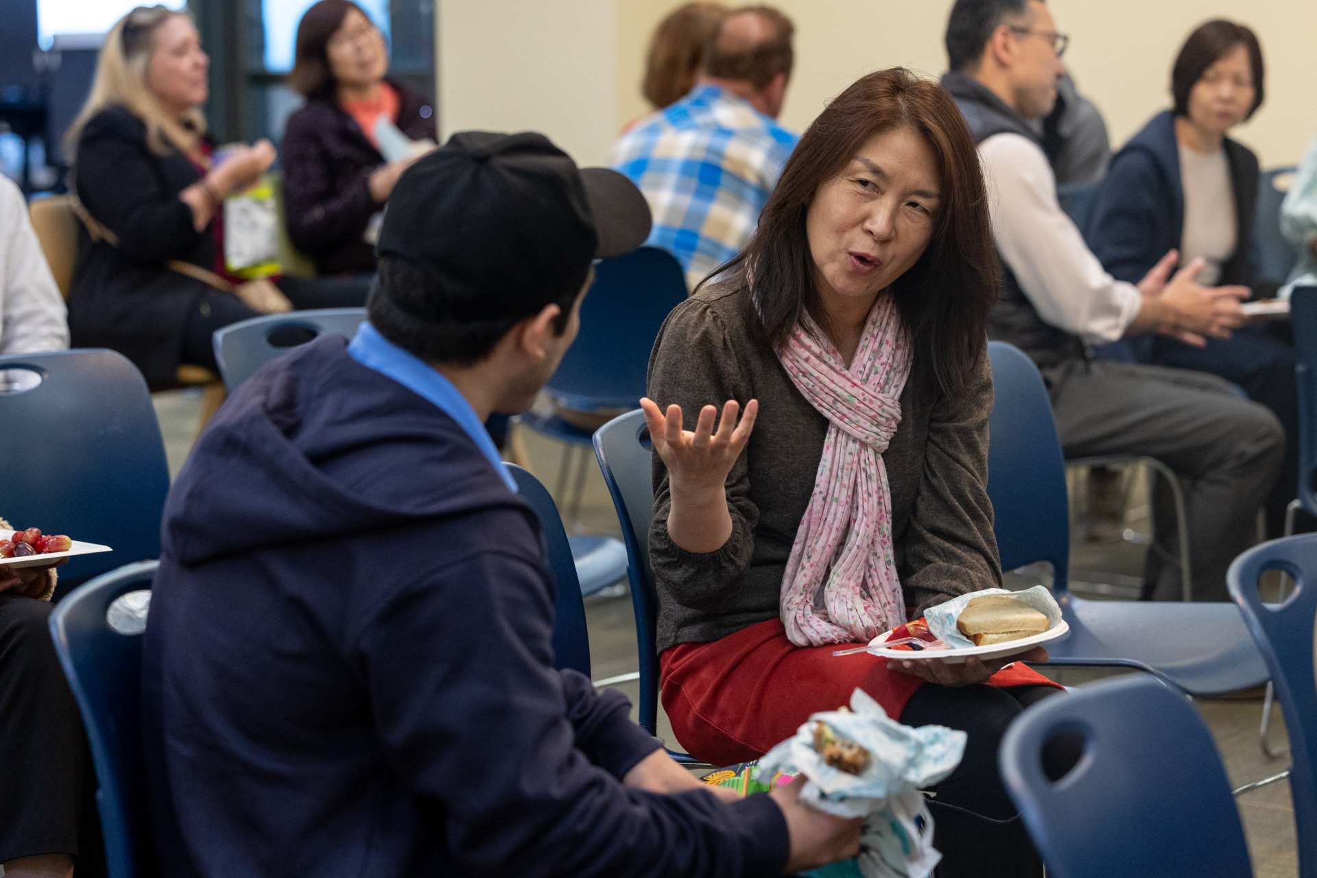 A woman is sitting and talking to a man during the lunch time event