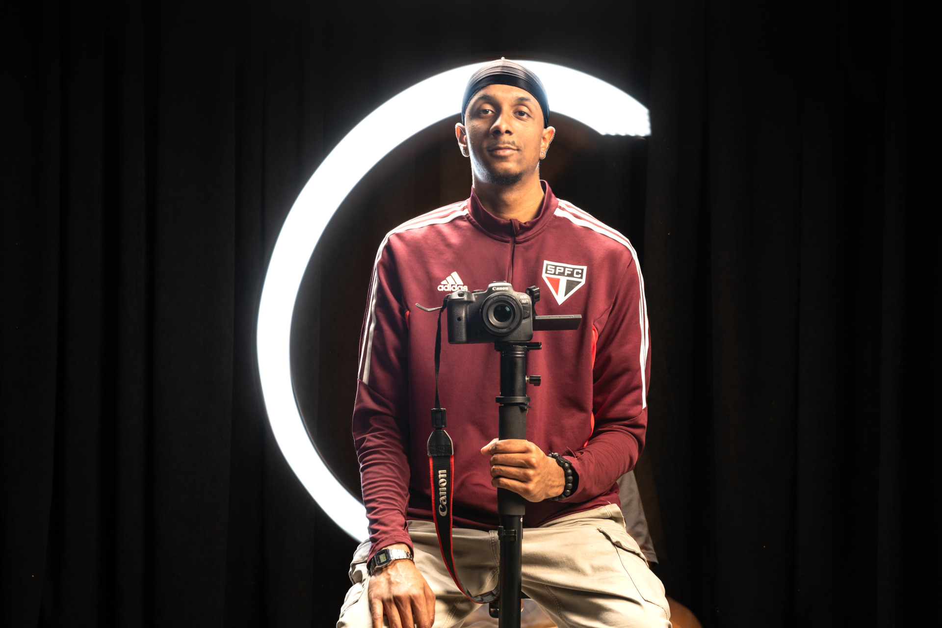 Lucas Colombo '27 holds a camera on a tripod and sits in front of a black backdrop.