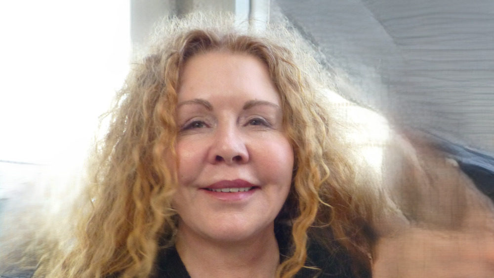 Linda Nieves smiles at the camera with curly brown hair.