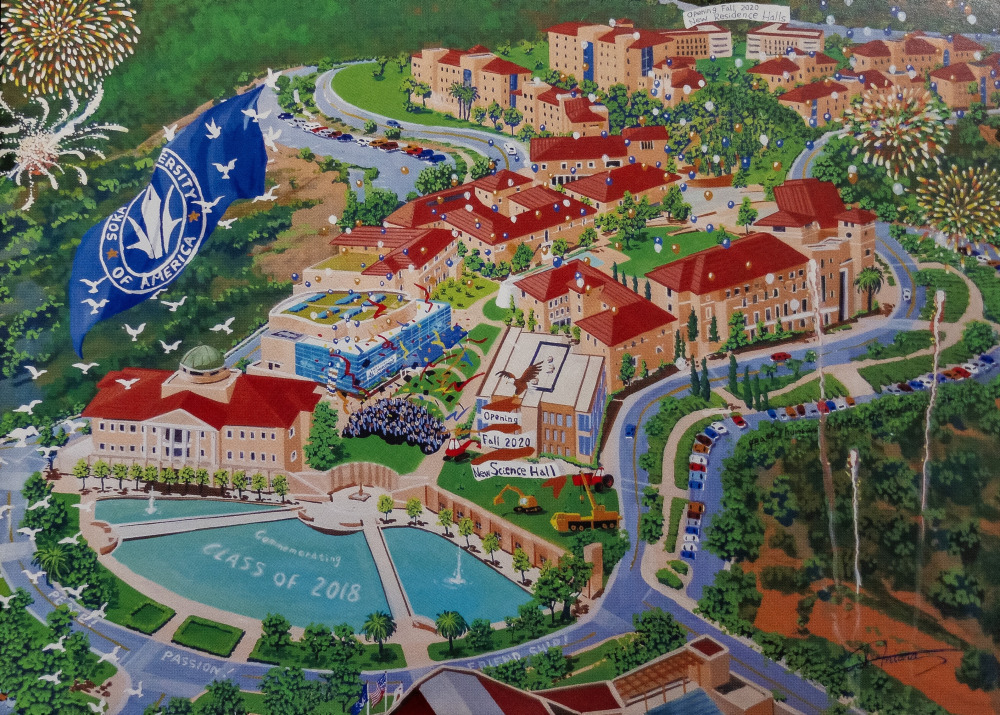 Postcard painting of an aerial view of SUA's campus with a blue and white SUA flag, fireworks, and "Commemorating Class of 2018" written in Peace Lake.