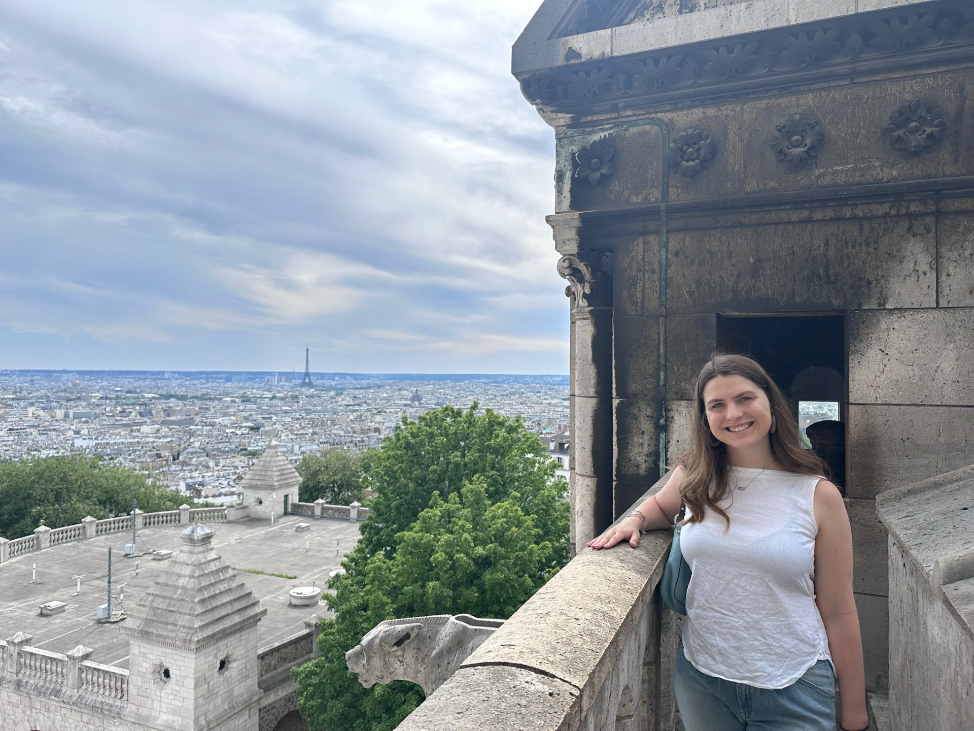 A girl poses at an overlook with the Eiffel Tower in the distance