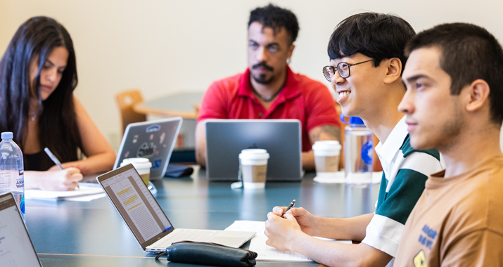 Four graduate students listen to their professor during a class.