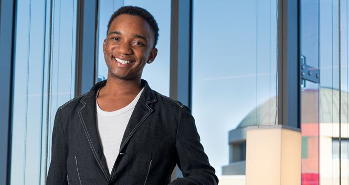 Muchindu Mwanayanda poses in front of glass windows in Curie Hall
