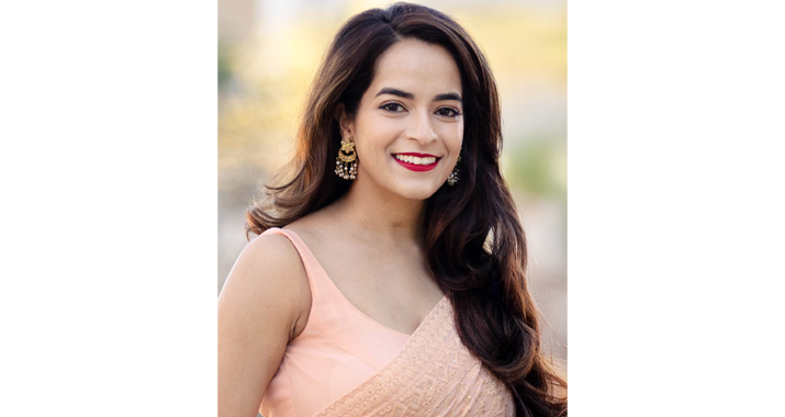 Nandini Puri wears a light pink dress and smiles for a photo