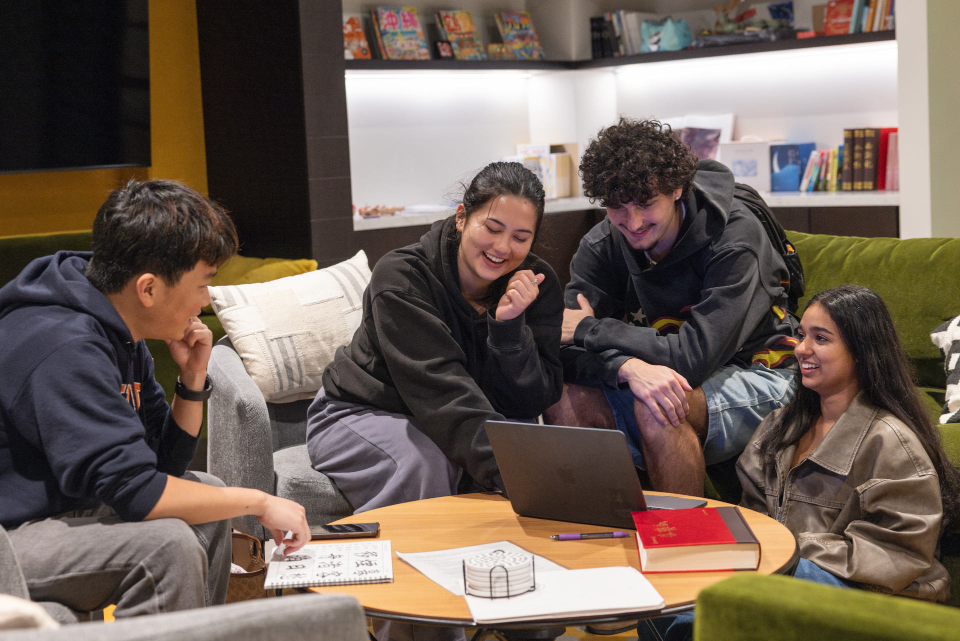 Four students laugh as they work on coursework together.