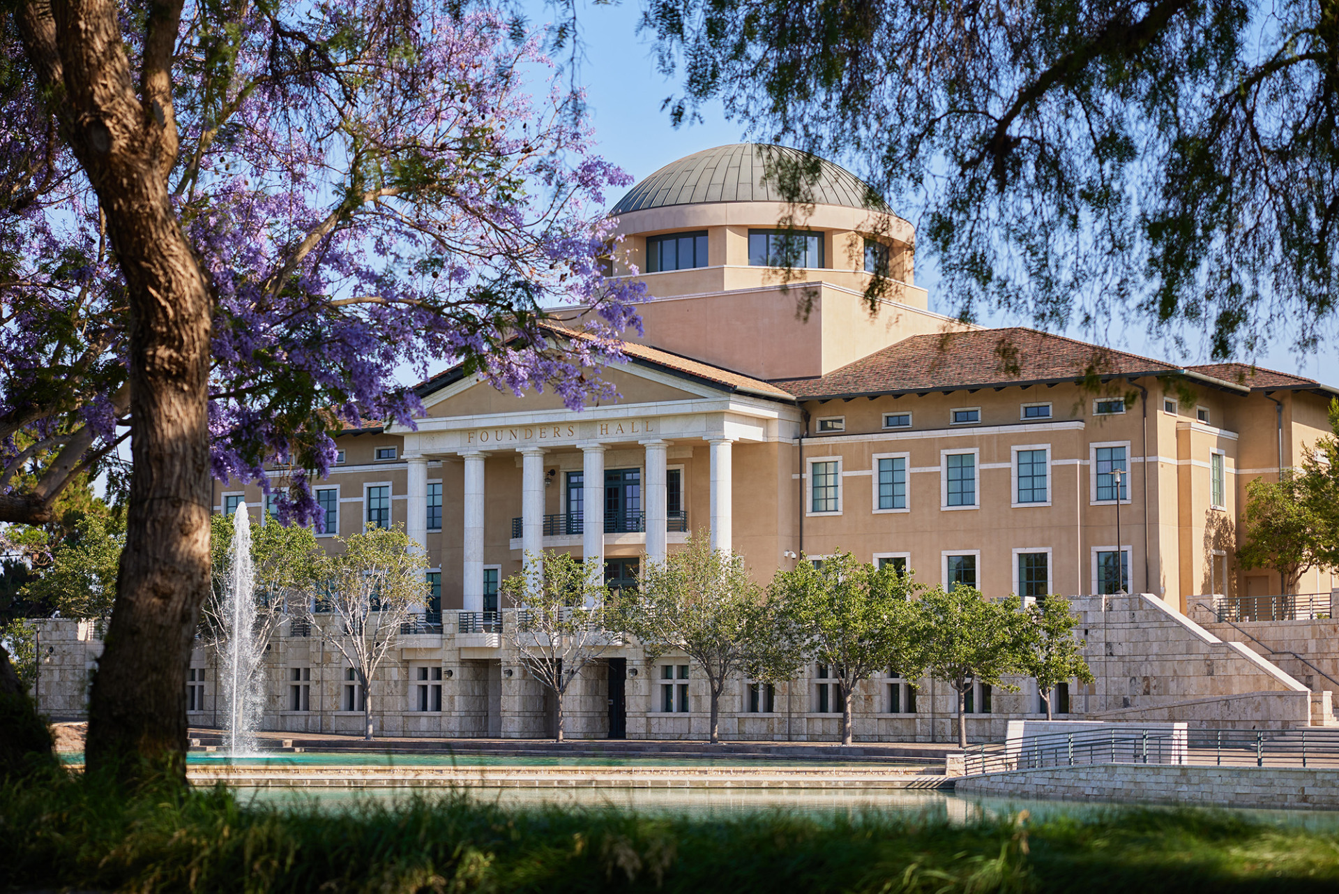 Founders Hall framed by a blooming Jacaranda tree.