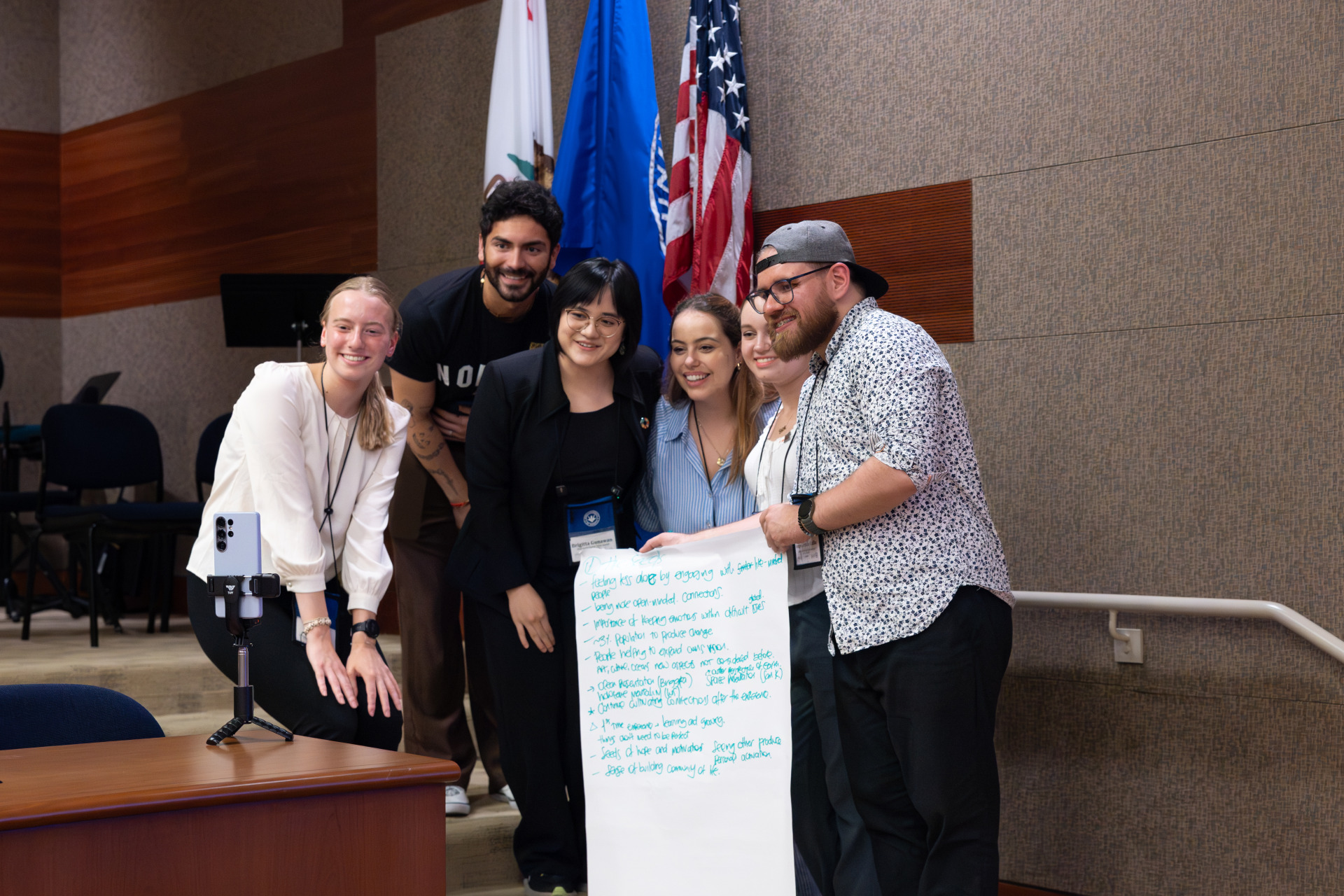 Six summit participants pose for a photo with a large poster paper after completing a group activity.