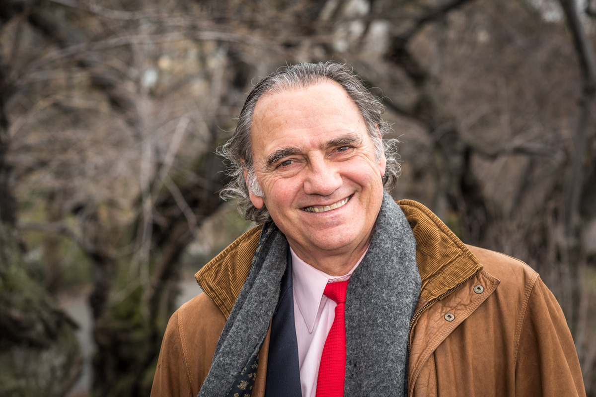 Carlos Alberto Torres smiles in Central Park wearing a grey scarf, brown corduroy jacket, with a light pink collared shirt and red tie. 