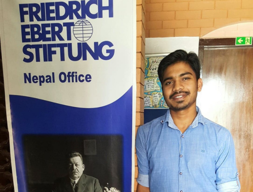 A male student standing next to a company standee 