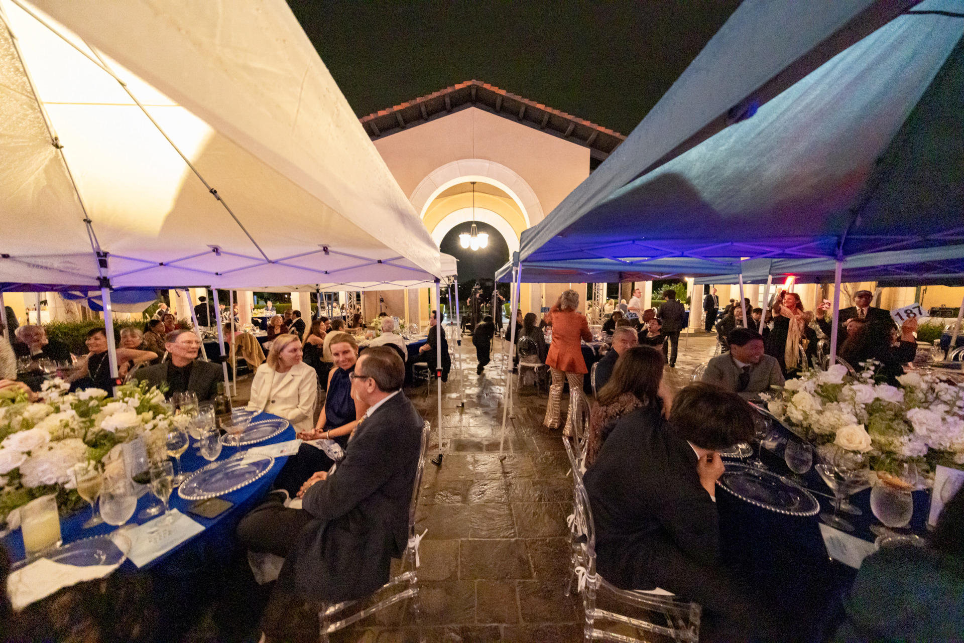 Pop-up tents stand over the ornately decorated gala tables as attendees sit during dinner outside on the athenaeum patio.
