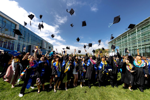 Graduating students toss their caps in the air celebrating commencement on SUA's campus.