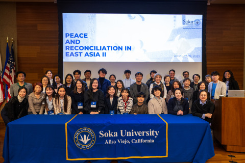 Participants of the 2025 Peace and Reconciliation in East Asia project symposium gather for a group photo in front of a Soka University banner.