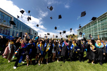 Graduating students toss their caps in the air celebrating commencement on SUA's campus.