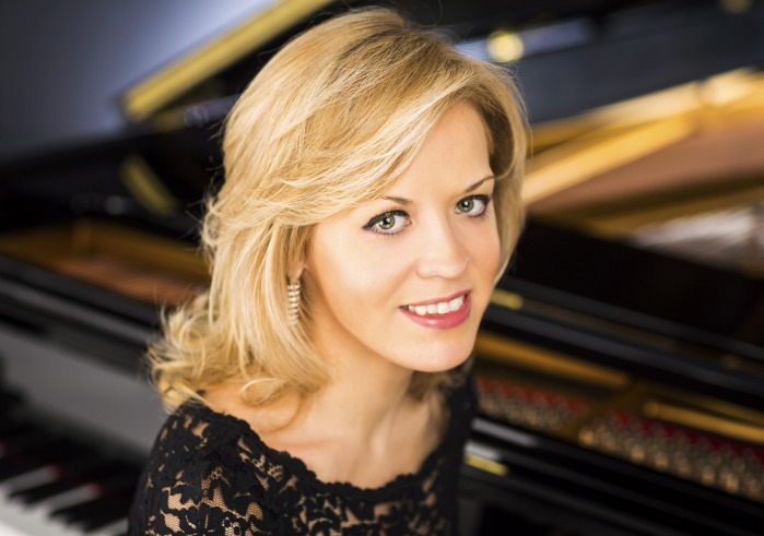 Olga Kern sitting at a piano wearing a black dress