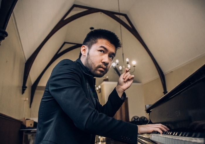 Conrad Tao sitting at a piano