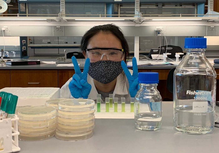 Woman flashing peace sign in bio lab