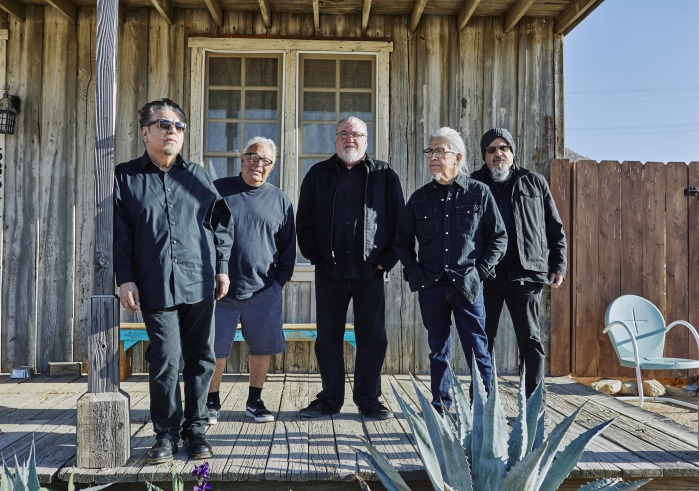 Los Lobos band against a gray western building