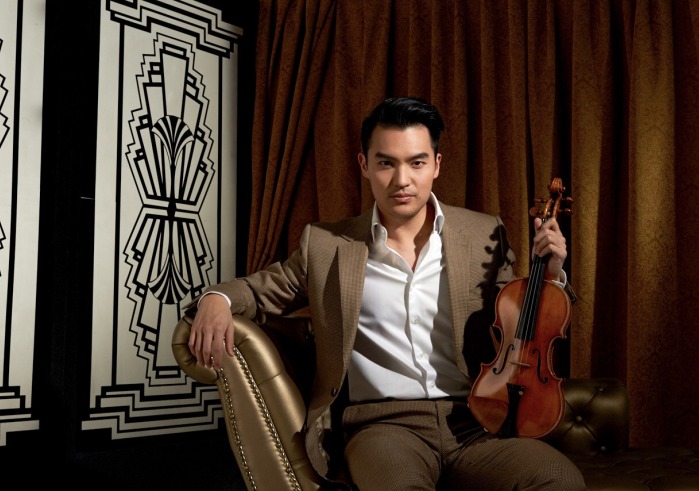 Man in brown suit sitting in chair holding a violin