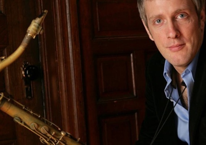 Man in black suit holding a sax
