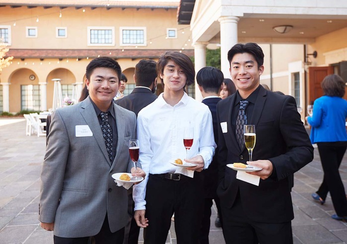 Soka students holding plate and wine glass during networking practice 