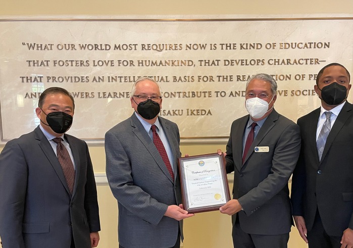 Men holding certificate of recognition in SUA Founders Hall 