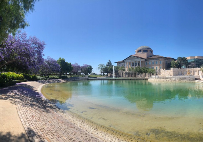 A photo of Founders Hall taken across Peace Lake surrounded by flowering purple trees