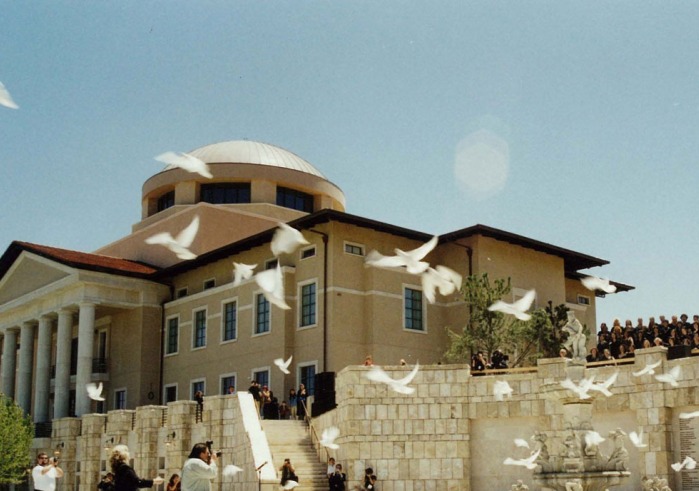 A flock of doves fly in front of Founders Hall