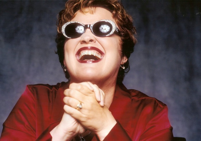 Woman in red suit with hands clasped laughing