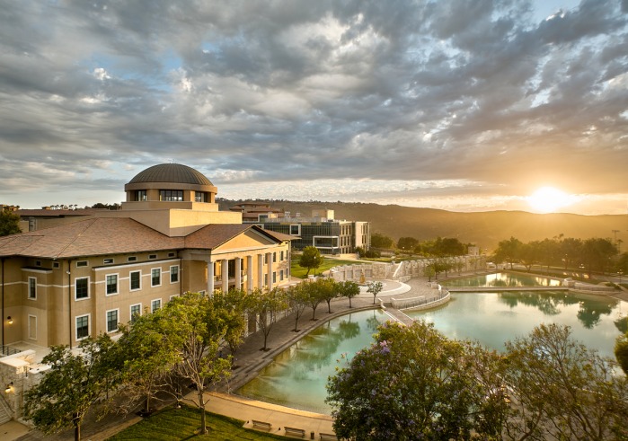 Aerial view of Founders Hall and Peace Lake with clouds and the sun on the horizon